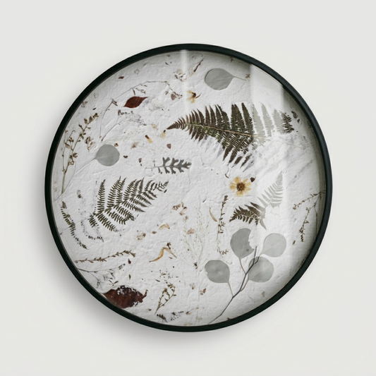 Joanna Jernajczyk for Nudiflorum R55/10 — circular botanical wall art with pressed ferns, eucalyptus, dried flowers and meadow botanicals on white textured ground, black metal frame, 55 cm