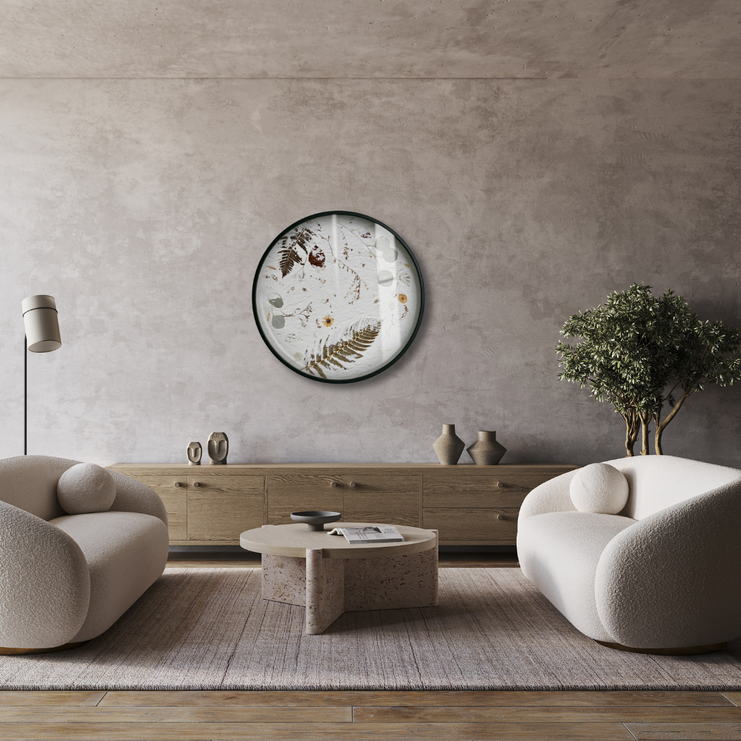 Nudiflorum R55/02 circular botanical wall art displayed on a raw concrete wall above a minimal living room with cream boucle armchairs and stone coffee table